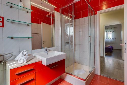 a red bathroom with a sink and a shower at Apartment A & J in Petrcane