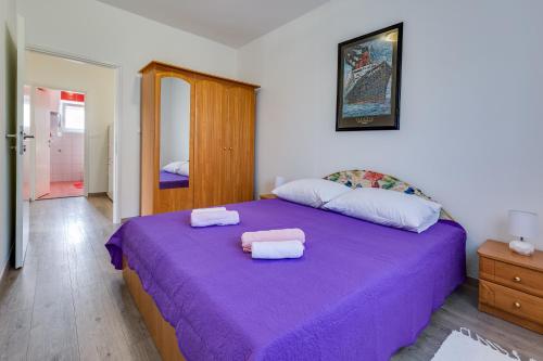 Un dormitorio con una cama morada con toallas. en Apartment A & J, en Petrčane