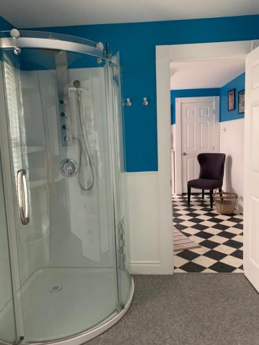 a bathroom with a glass shower with a black chair at THE YORK HOUSE in Fort Erie
