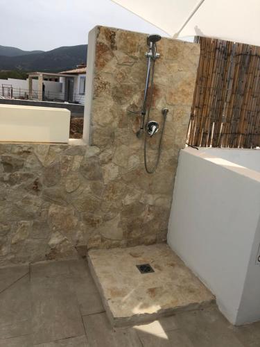 y baño con ducha y pared de piedra. en VILLA AMBRA, en Tertenìa