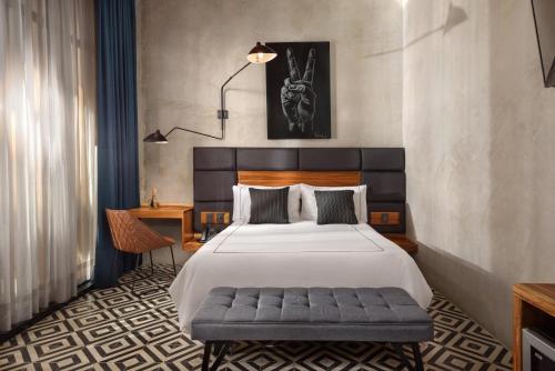 a bedroom with a bed and a bench in it at Diez Diez Collection in Mérida