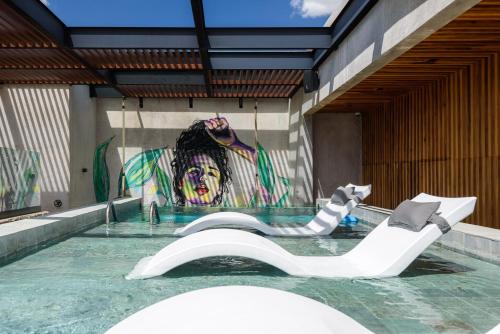 a swimming pool with a white chair in front of a painting at Diez Diez Collection in Mérida