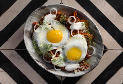 a plate of food with eggs on a table at Diez Diez Collection in Mérida