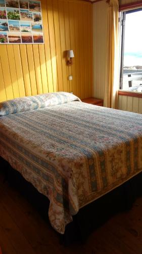 a bedroom with a bed with a blanket on it at El Rincon de Las Pleyades in El Quisco