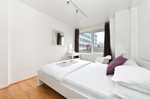 ein weißes Schlafzimmer mit einem großen weißen Bett und einem Fenster in der Unterkunft Oxford Street & Carnaby - Soho Abode Apartments in London