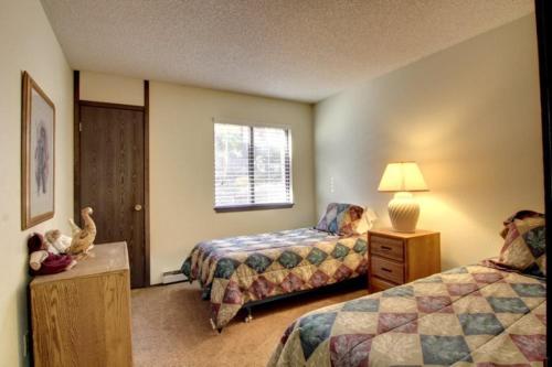 a bedroom with two beds and a dresser and a window at Giant Steps 34 Ski In-out in Brian Head
