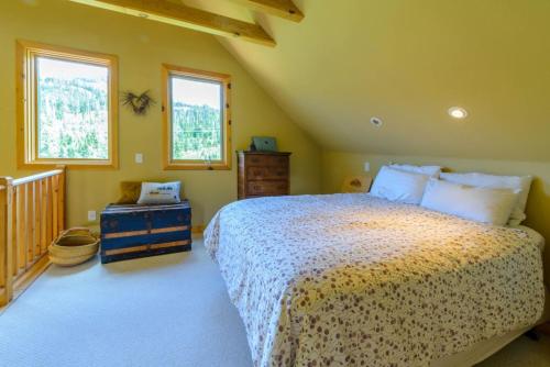 1 dormitorio con 1 cama grande y 2 ventanas en Bristlecone Cabin, en Brian Head