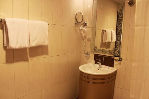 a bathroom with a sink and a mirror and towels at Alolayan Plaza Hotel in Mecca