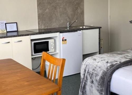 a kitchen with a microwave and a refrigerator and a table at Chevron Motel in Taupo