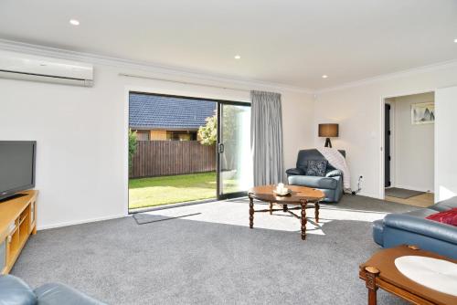 a living room with a blue couch and a table at Lavandula 4 - Christchurch Holiday Homes in Christchurch