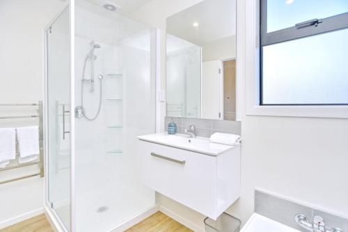 a white bathroom with a sink and a shower at Lavandula 4 - Christchurch Holiday Homes in Christchurch