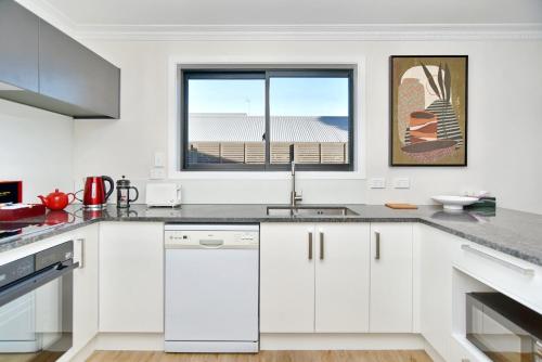 a white kitchen with a sink and a window at Lavandula 4 - Christchurch Holiday Homes in Christchurch