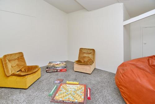 a living room with two chairs and a chess board on the floor at Lavandula 4 - Christchurch Holiday Homes in Christchurch
