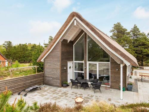een huis met een rieten dak en een patio bij 6 person holiday home in R m in Toftum