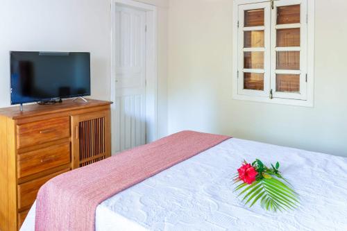 a bedroom with a bed with a television and a flower on it at Pousada Rio da Vila in Porto Seguro