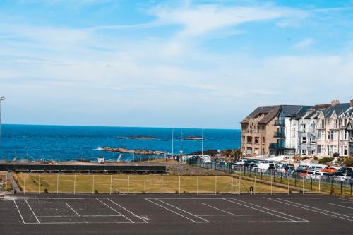a parking lot with a tennis court in front of the ocean at Luxury Sea View Apartment in Portrush
