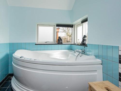 a bathroom with a white tub and blue tiles at 8 person holiday home in Glesborg in Glesborg