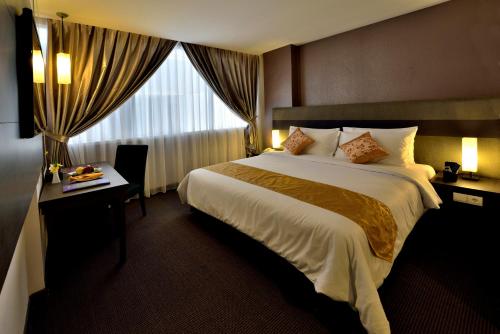 a hotel room with a large bed and a window at Tjokro Hotel Pekanbaru in Pekanbaru