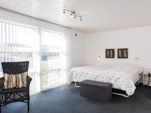 een slaapkamer met een bed, een stoel en ramen bij Holiday home Fanø XCVIII in Fanø