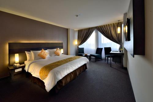 a hotel room with a large bed and a desk at Tjokro Hotel Pekanbaru in Pekanbaru