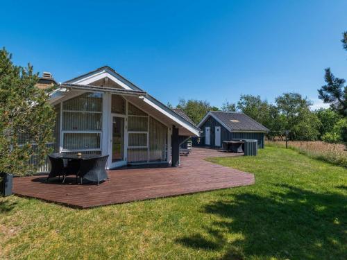 a house with a wooden deck in a yard at Secluded Haven in Rindby in Fanø