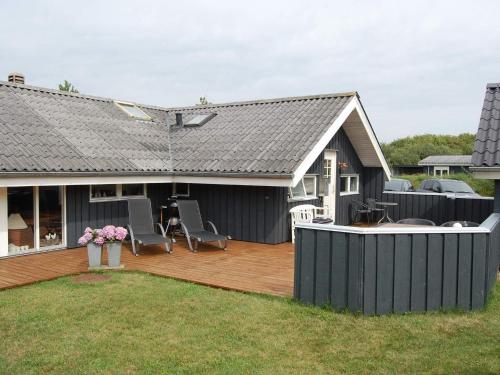 a house with a wooden deck with chairs on it at Secluded Haven in Rindby in Fanø