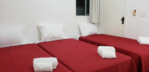 two beds with red sheets in a white room at LIVE IN FORTALEZA HOTEL in Fortaleza