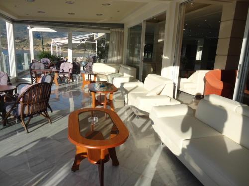 a balcony with white furniture and tables and chairs at New Aegli Resort Hotel in Poros
