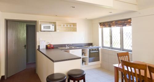 a kitchen with a sink and a counter with chairs at Camelot Motor Lodge in Christchurch