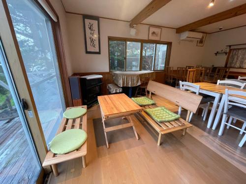 a room with wooden tables and chairs and windows at Guest House Chaconne Karuizawa in Karuizawa