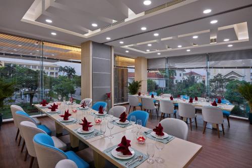 a dining room with long tables and chairs and windows at Khách sạn SAM Quảng Bình in Dong Hoi
