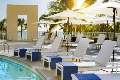 a pool with chairs, tables and umbrellas at The Twin Fin Hotel in Honolulu