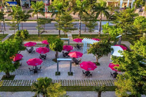 a group of tables with pink umbrellas in a park at Khách sạn SAM Quảng Bình in Dong Hoi