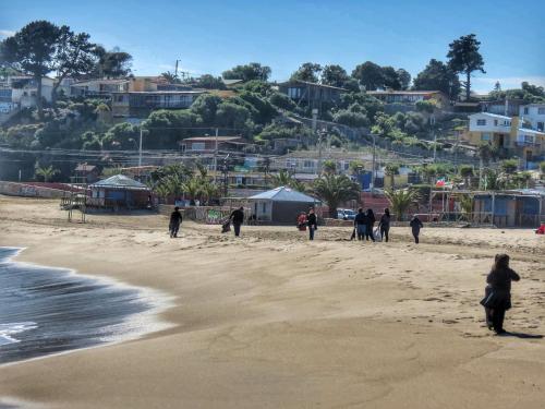 a group of people walking on the beach at El Rincon de Las Pleyades in El Quisco
