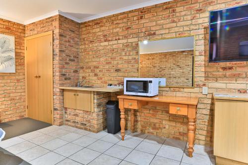 a room with a brick wall and a desk with a microwave at Wonthaggi Motel in Wonthaggi