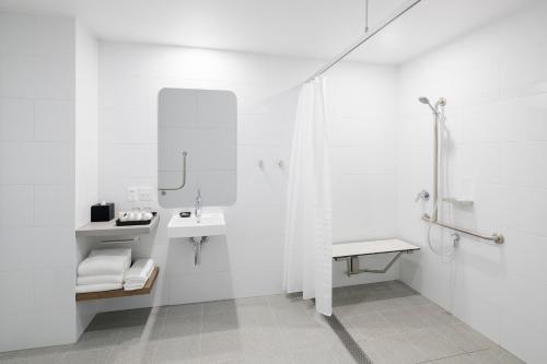 Baño blanco con lavabo y espejo en Holiday Inn Sydney St Marys, an IHG Hotel en St Marys