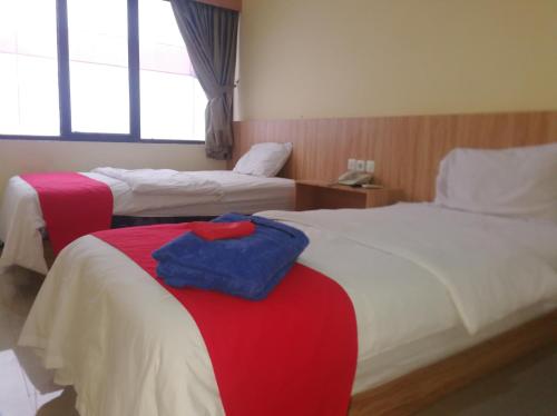 Habitación de hotel con 2 camas en rojo y blanco en Hotel Mayang Sari 2 en Jambi