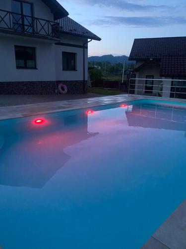 a swimming pool with blue and red lights in front of a house at Карпатский уикенд in Slavske
