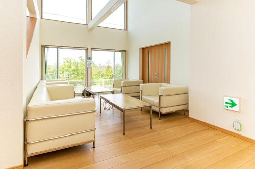 a waiting room with chairs and a table and windows at Tabist Hotel Takagiya Iwaki in Hisanohama