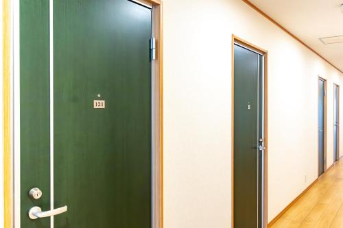 a green door in a room with a hallway at Tabist Hotel Takagiya Iwaki in Hisanohama