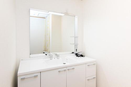 a bathroom with a white sink and a mirror at Tabist Hotel Takagiya Iwaki in Hisanohama