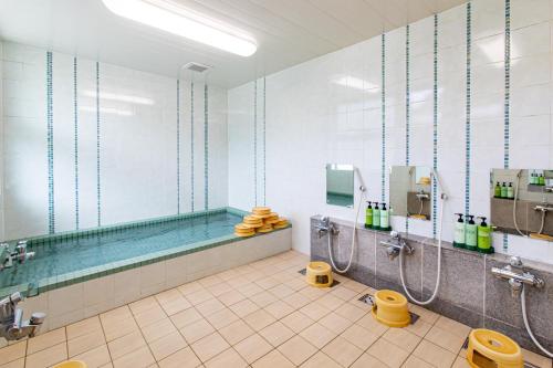 a bathroom with a tub and a swimming pool at Tabist Hotel Takagiya Iwaki in Hisanohama