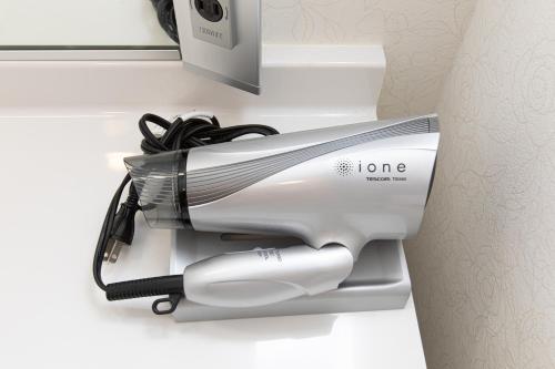 a hair dryer sitting on the side of a toilet at Tabist Hotel Takagiya Iwaki in Hisanohama