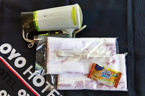 a hair dryer and towels with a blow dryer and toothpaste at Tabist Hotel Takagiya Iwaki in Hisanohama