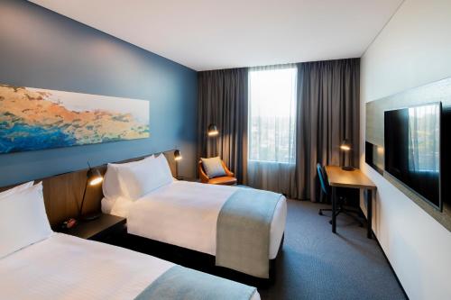 um quarto de hotel com duas camas e uma televisão de ecrã plano em Holiday Inn Sydney St Marys, an IHG Hotel em St Marys