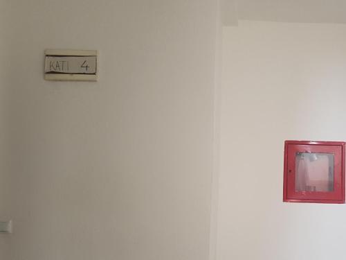 a clock on a white wall with a sign on it at Redon Apartment in Pristina