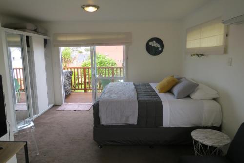 a bedroom with a bed and a balcony at Two Palms in Gisborne