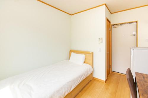 a small bedroom with a bed and a sliding door at Tabist Hotel Takagiya Iwaki in Hisanohama