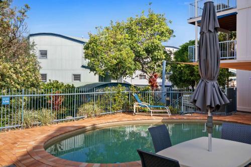 a pool with an umbrella and a table and chairs at Castaway Cove Beachfront Home by Stay Noosa in Marcus Beach