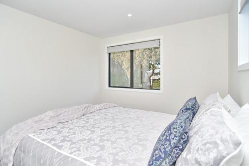 a white bedroom with a bed and a window at Lavandula 3 - Christchurch Holiday Homes in Christchurch